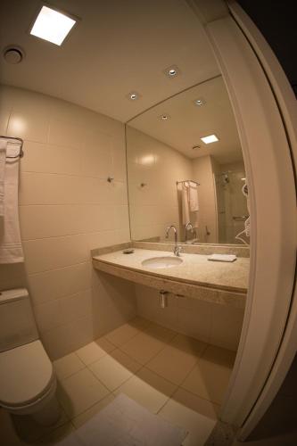 a bathroom with a sink and a toilet and a mirror at Hellix Flat Itaboraí in Itaboraí