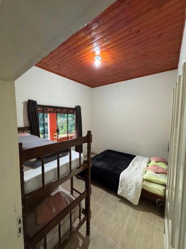 Un dormitorio con dos literas y techo de madera. en Hostel da Verinha, en Itamonte