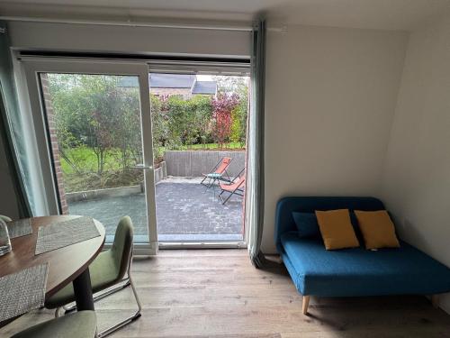 a living room with a blue couch and a sliding glass door at Appart Wavre, 2ch, terrasse, piscine, charme & confort in Wavre
