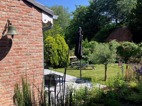 an umbrella in a garden next to a brick building at Tampico, Holiday Home at river Schelde in Hamme