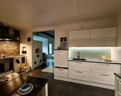 une grande cuisine avec des armoires blanches et une table dans l'établissement Lapland Oasis, à Rovaniemi