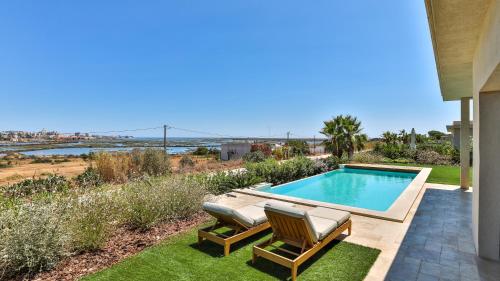 a backyard with a swimming pool and two lawn chairs at Brand New Waterfront Villa with pool in Faro