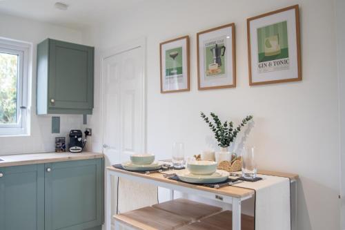 a kitchen with blue cabinets and a table with dishes on it at Sizewell C - Contractor Accommodation in Leiston