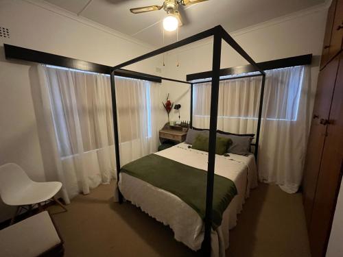 Un dormitorio con una cama con dosel y una silla. en Summer Suite, en Hermanus