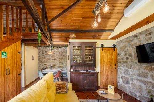 a living room with wooden ceilings and a stone wall at Quintinha do Varoso - Little Red Cottage House in São Pedro do Sul