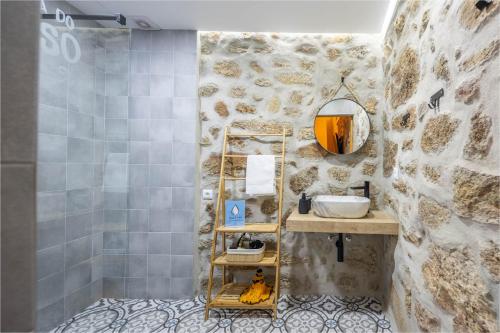 ein Badezimmer mit einem Waschbecken und einer Steinmauer in der Unterkunft Quintinha do Varoso - Little Red Cottage House in São Pedro do Sul