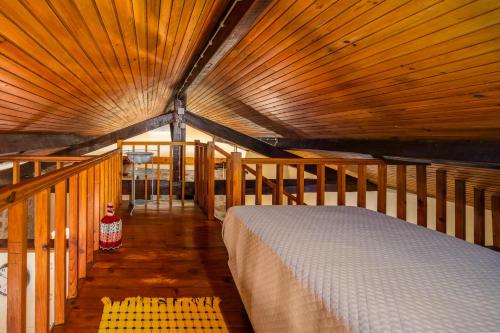 ein Bett in einem Zimmer mit Holzdecke in der Unterkunft Quintinha do Varoso - Little Red Cottage House in São Pedro do Sul
