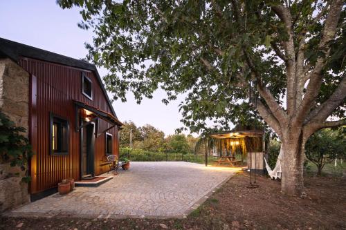 a house with a pavilion next to a tree at Quintinha do Varoso - Little Red Cottage House in São Pedro do Sul