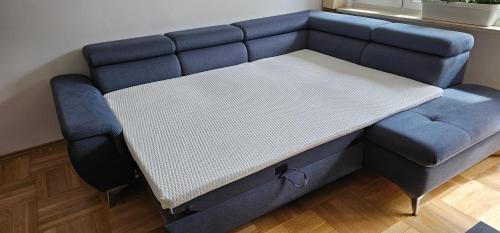 a bed with a blue couch in a room at Apartament Gdynia Babie Doły in Gdynia