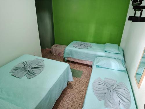 two beds in a room with green walls at Pousada Nosso Cantinho in Guarapari