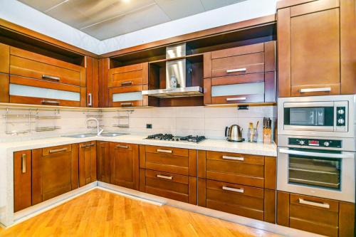 une cuisine avec des armoires en bois et des appareils électroménagers blancs dans l'établissement Apartment STEL, à Baku