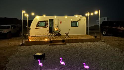 a white trailer parked in a parking lot at night at Flamingo Caravan in Ash Shāb