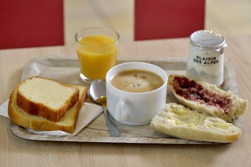 CuincyにあるPremiere Classe Lille Sud - Douai Cuincyのコーヒーとパンとオレンジジュースが入ったトレイ