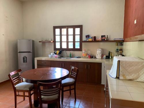 a kitchen with a table and chairs and a refrigerator at Habitacion chica con piscina in Mérida