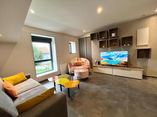 a living room with a couch and a flat screen tv at Le Spacieux gare d'Oullins - 2 chambres - 3 lits - Parking privé in Pierre-Bénite