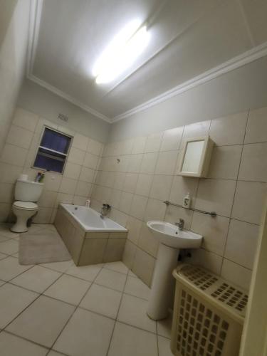a bathroom with a sink and a tub and a toilet at Nestville apartment in Solwezi