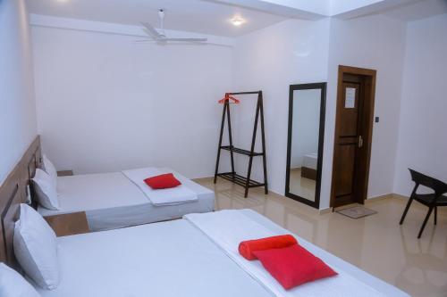 ミリッサにあるOcean Light Mirissaのベッド2台、デスク、鏡が備わる客室です。