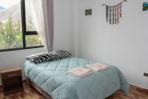 a bedroom with a blue bed with two towels on it at Valle Sagrado Mágico in Urubamba