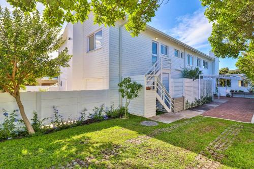 una casa blanca con una escalera en un patio en White Penguin, en Stilbaai