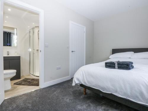a white bedroom with a bed and a bathroom at Caledfryn in Benllech