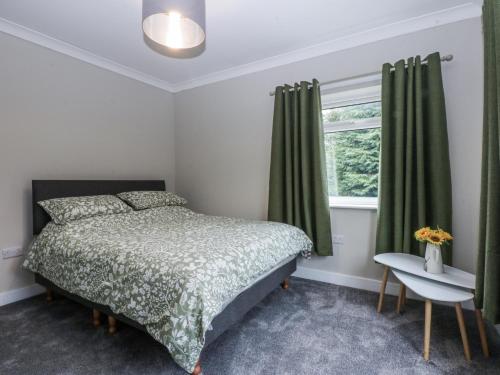a bedroom with a bed and a window with green curtains at Caledfryn in Benllech