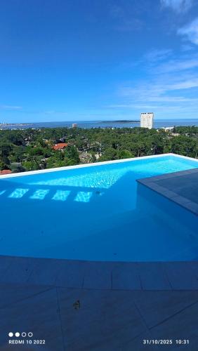 a blue swimming pool with a view of the ocean at Apartamento Acapulco in Punta del Este