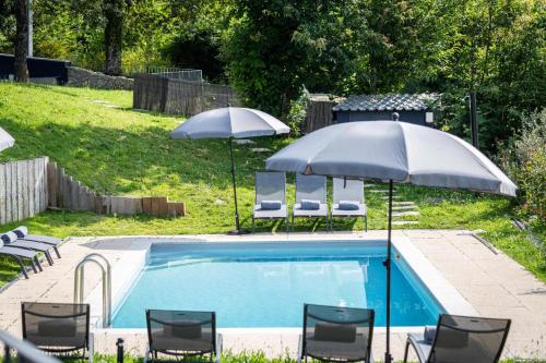 twee parasols en stoelen naast een zwembad bij Casas Bouro 1 Casa Das Hortências in Balança