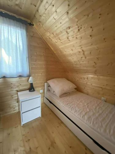 a bed in a wooden room with a window at Sister's House Zator in Zator