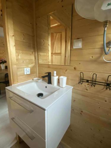 a bathroom with a white sink in a wooden room at Sister's House Zator in Zator