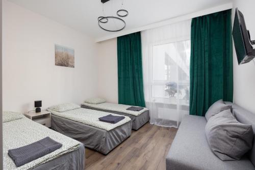 a room with two beds and a couch and a window at Pokoje Warszawski Świt in Warsaw