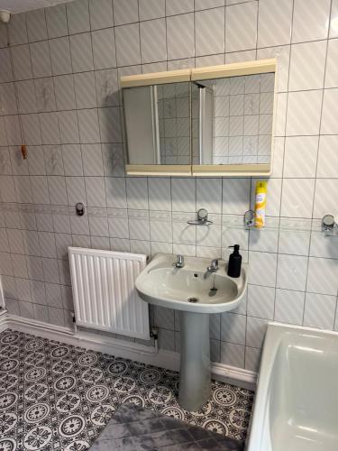 a bathroom with a sink and a mirror and a tub at Spacious 3 Bedroom House in Doncaster with Vintage Charm in Doncaster