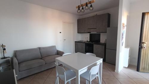 een woonkamer met een bank en een tafel en een keuken bij Appartamento Polpenazze - Relax in collina con piscina in Polpenazze del Garda