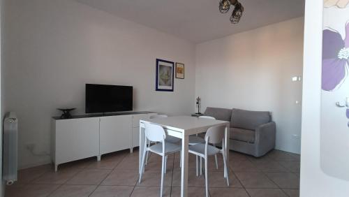 een woonkamer met een tafel, een tv en een bank bij Appartamento Polpenazze - Relax in collina con piscina in Polpenazze del Garda