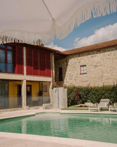 a house with a swimming pool in front of a building at Casa Lata - Agroturismo e Enoturismo in Amares