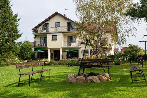 a house with a tree and benches in the yard at Willa Pod Lasem in Tupadły
