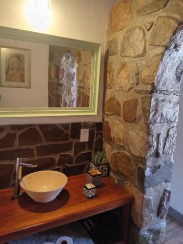 Un baño con pared de piedra y un lavabo sobre una encimera de madera. en Cabañas La Nochera, en Tilcara