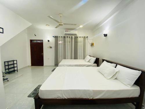 two beds in a room with white walls at Seavora Tangalle in Tangalle