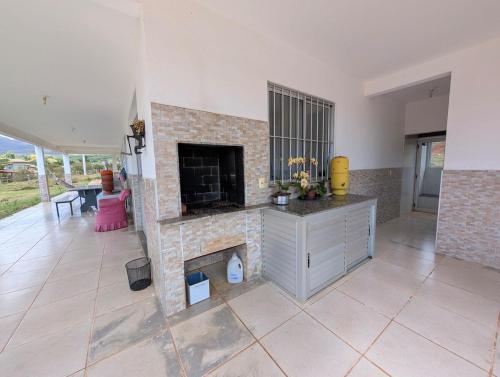 a living room with a fireplace and a table at Sítio Vista Azul - Lazer e descanso na natureza in Mateus Leme