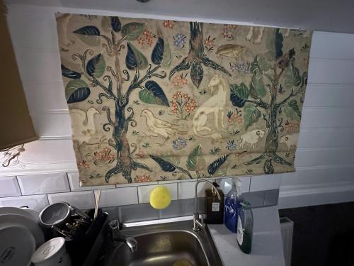 a tapestry hanging over a sink in a kitchen at BrightOwl Waterside Narrowboat Cottage Experience in Thorpe