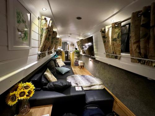 a living room with a black couch in a room at BrightOwl Waterside Narrowboat Cottage Experience in Thorpe