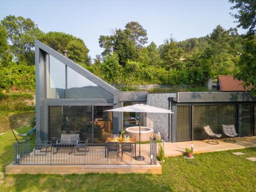 a house with a deck with a table and an umbrella at Casas De Bouro 3 Casa Do Alecrim in Terras de Bouro
