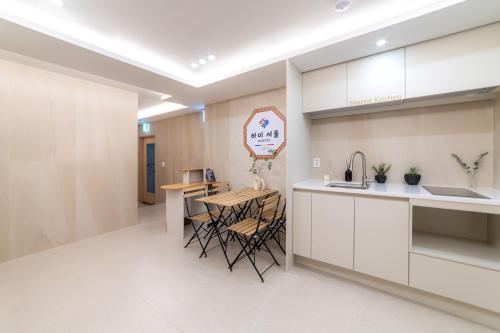 Una cocina con gabinetes blancos y una mesa y sillas. en Hi Seoul Hostel West, en Seúl