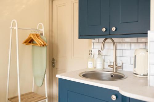 a kitchen with a sink and blue cabinets at Delabere House - Luxury Cotswolds Holiday Apartments in Moreton in Marsh