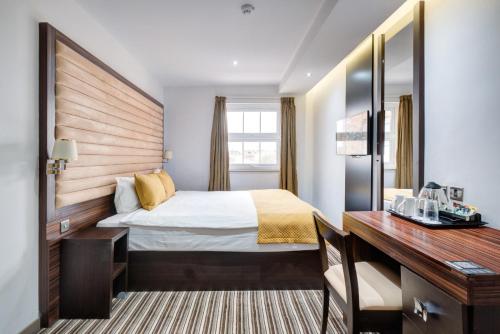 ロンドンにあるMaitrise Hotel Maida Vale - Londonのベッドと机があるホテルの部屋