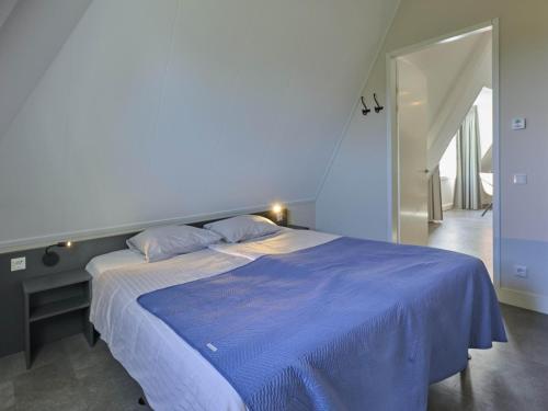 a bed in a bedroom with a blue comforter at SeaLuxe Suite 27i in Colijnsplaat