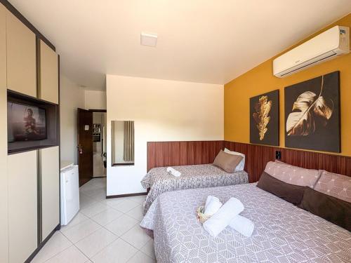 a hotel room with two beds and a tv at Hospedagem com café da manhã - Quarto 1 - Hospedaria Orquídeas de Bombinhas in Bombinhas