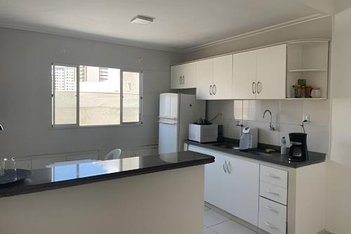 een keuken met witte kasten en zwarte aanrechtbladen bij CeoHost Studios Premium in Aracaju
