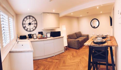 eine Küche und ein Wohnzimmer mit einem Sofa und einer Uhr in der Unterkunft Little Dunton Lodges 2 in Brentwood
