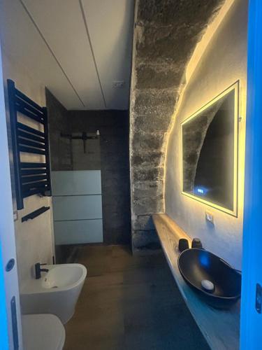 ETNA HOUSE LUXURY con giardino e vasca idromassaggio في لينغواغلوسا: حمام مع حوض غسيل أسود ومرحاض