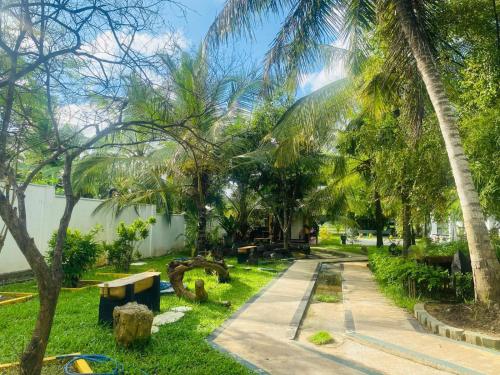 a path through a park with palm trees at Jasmine Chill Cafe & Guest House in Chilaw